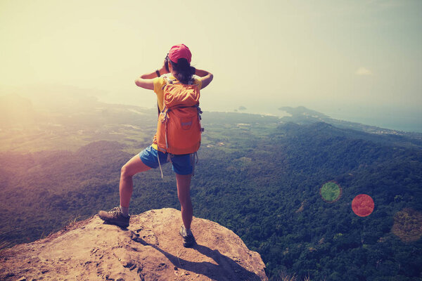successful woman hiker standing on mountain peak cliff edge