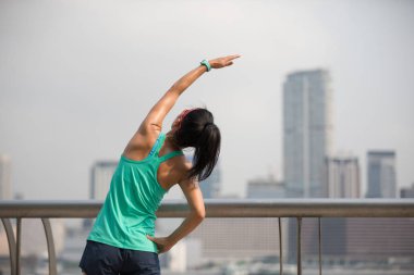 Sisli şehirde kollarını esneten kadın koşucunun sağlıklı yaşam tarzı  