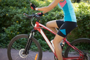 Güneşli bir günde bisiklet sürerken akıllı telefon kullanan bir kadın