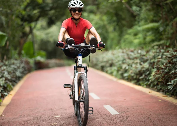 Female cyclist riding mountain bike outdoors, having fun with legs on handlebar