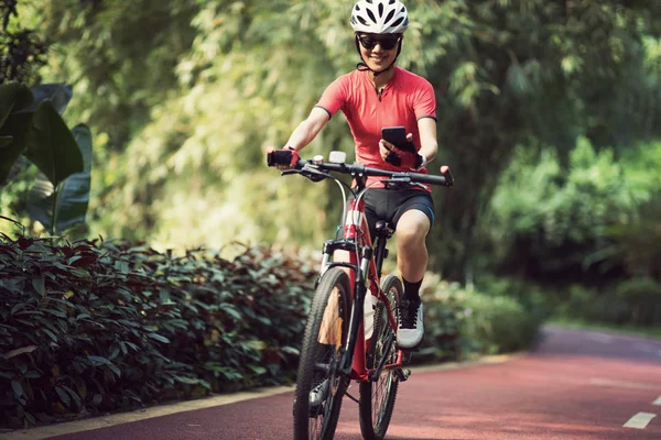 Güneşli Bir Günde Bisiklet Sürerken Akıllı Telefon Kullanan Bir Kadın — Stok fotoğraf