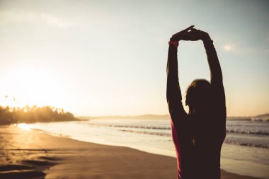 Fit dişi sörfçü sörf yapmadan önce sahilde ısınıyor.