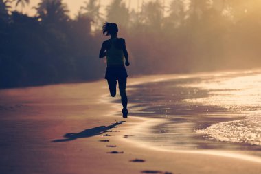 Gün doğumu plajda çalışan fitness kadın