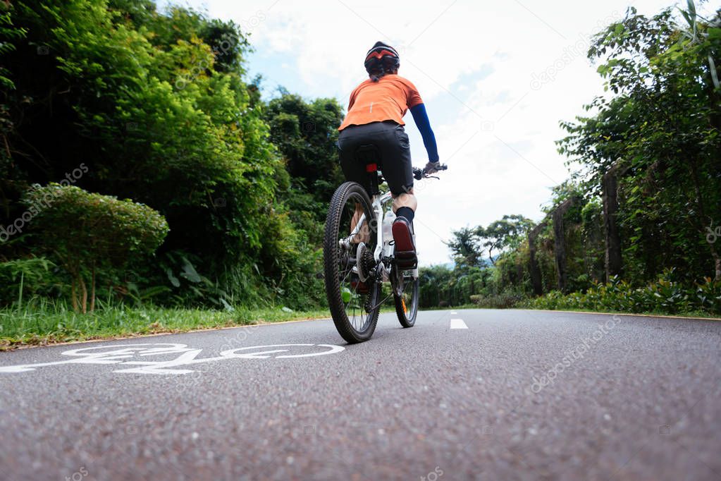 Female cyclist riding mountain bike on tropical rainforest trail