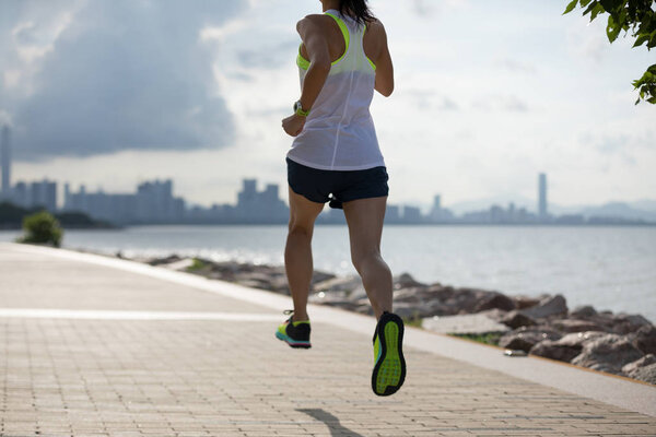 Fitness woman running and training for marathon on sunny coast trail
