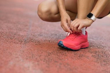 Park yolunda ayakkabı bağı bağlayan kadın koşucu