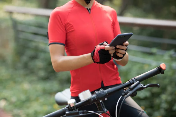 晴れた日に自転車に乗っている間にスマートフォンを使用して女性の作物 — ストック写真