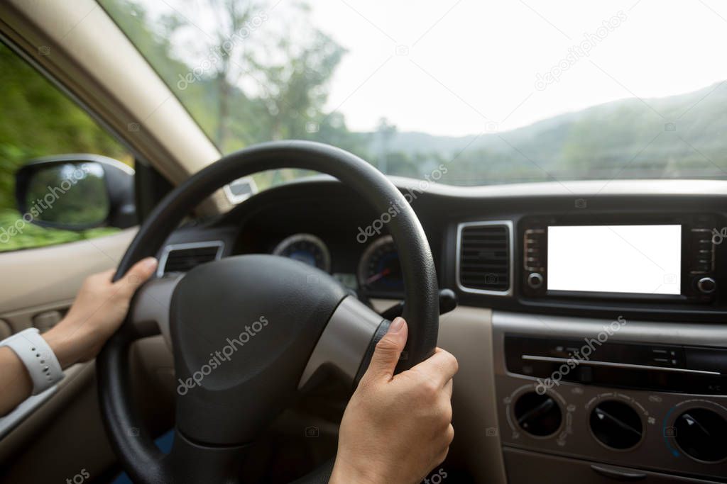 Hands of woman driving car on country road 