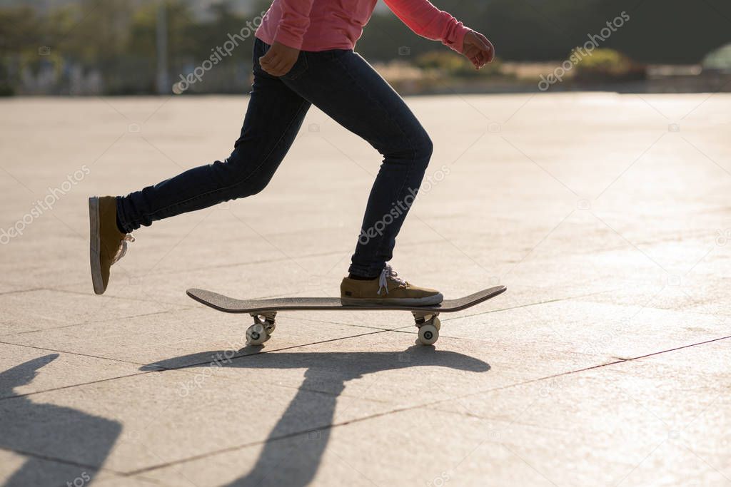 Low angle of skateboarder riding board in urban city at sunset
