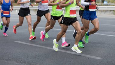 Şehir yolunda koşan erkek maraton koşucuları