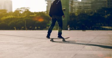 Şehir merkezinde gün batımında kaykay yapan bayan sporcu