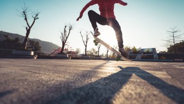 Şehir merkezinde gün batımında kaykayla atlayan tanınmayan biri.