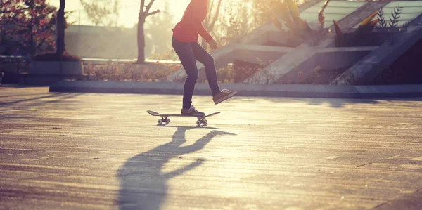 Unrecognizable woman skateboarding at sunset in urban city