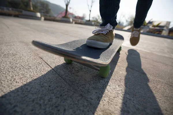 Unrecognizable woman skateboarding at sunset in urban city