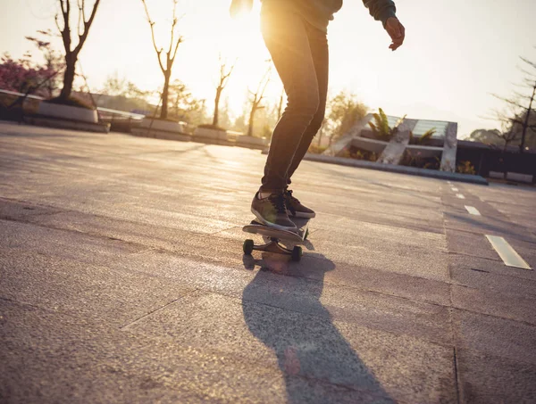 Unrecognizable woman skateboarding at sunset in urban city