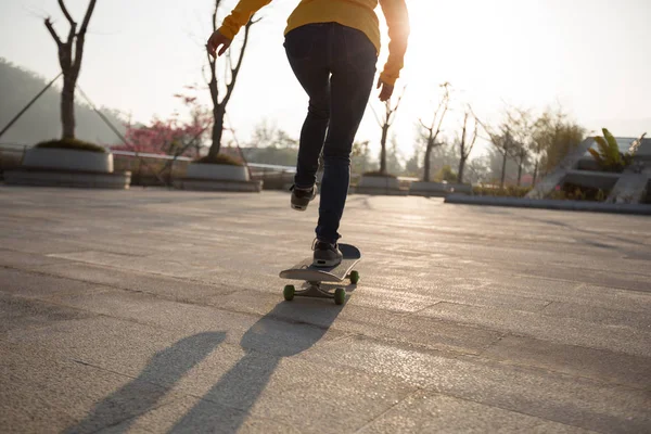 Unrecognizable woman skateboarding at sunset in urban Chinese city