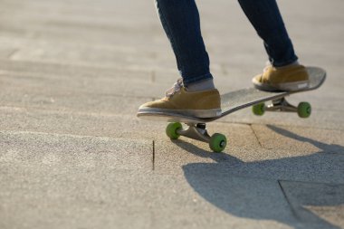 Gün batımında şehir parkında kaykaycı kadınların bacakları.