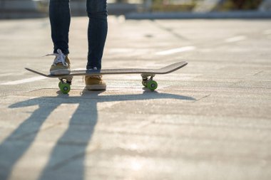 Kadın kaykaycıların bacakları gün batımında şehir parkındaki yolda.