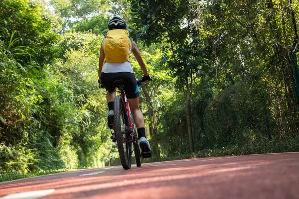 阳光明媚的白天 骑背包在公园自行车道上骑车的女人 — 图库照片