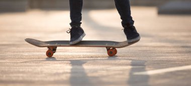 Şehir merkezinde gün doğumunda kaykay yapan sıradan kadın kaykaycıların bacakları.