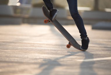 Şehir merkezinde gün doğumunda kaykay yapan sıradan kadın kaykaycıların bacakları.