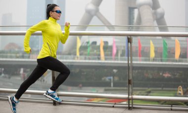 Young fitness woman running on bridge of Shanghai city, China