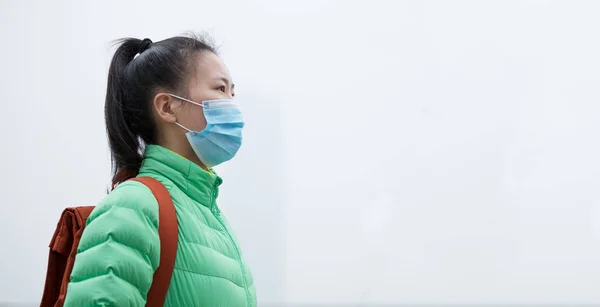 緑のジャケットと顔のマスクで心配アジアの女性は公害霧と街を離れて見て — ストック写真