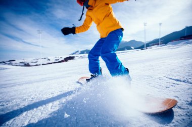Kış dağlarında kar kayağı yapan renkli giysili kadın snowboardcu.