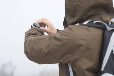 Sisli dağın tepesinde kadın yürüyüşçü yüksekliği kontrol ediyor.