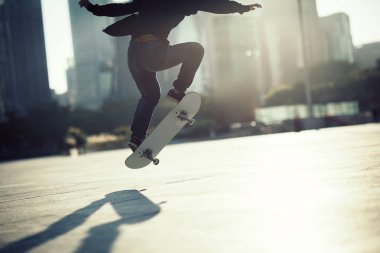 Çin şehrinin şehir merkezinde günbatımında şık bir kadın kaykay yapıyor.