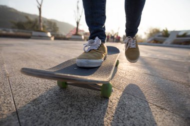 Güneş doğarken kaykay parkında çalışan kadın kaykaycı bacakları.