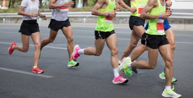 Şehir yolunda koşan maraton koşucuları.