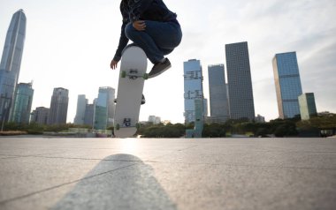 Çin 'in şehir merkezinde günbatımında kaykay yapan zarif genç bir kadın.