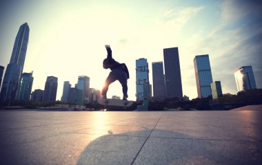 Çin 'in şehir merkezinde günbatımında kaykay yapan zarif genç bir kadın.