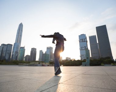 Çin 'in şehir merkezinde günbatımında kaykay yapan zarif genç bir kadın.