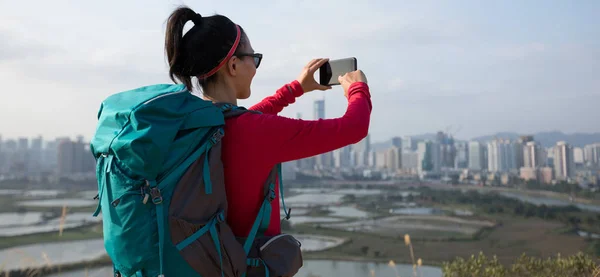 深圳近现代城市旁边 女性徒步旅行者正在用智能手机拍照 — 图库照片