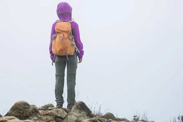 Woman hiking on foggy mountain top