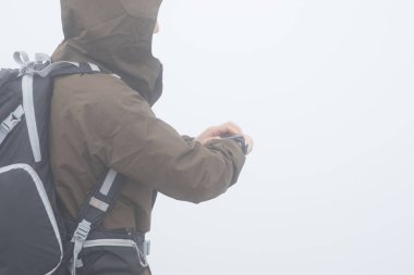 Sisli dağın tepesinde kadın yürüyüşçü yüksekliği kontrol ediyor.