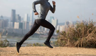 Modern şehrin yanındaki dağlarda koşan bayan sporcu.