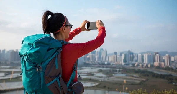 深圳近现代城市旁边 女性徒步旅行者正在用智能手机拍照 — 图库照片