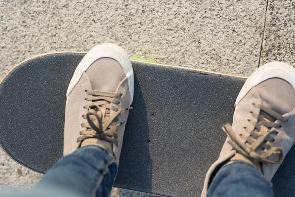 Looking down of female feet on skateboard in street