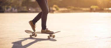 Gündoğumunda şehir meydanında kaykay yapan sıradan bir bayan kaykaycı.