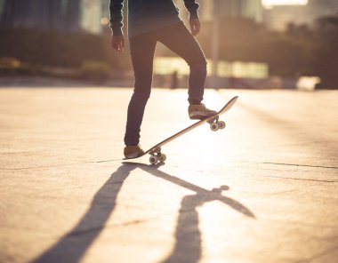 Gündoğumunda şehir meydanında kaykay yapan sıradan bir bayan kaykaycı.