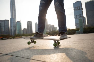 Gündoğumunda şehir meydanında kaykay yapan sıradan bir bayan kaykaycı.