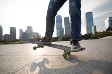 Gündoğumunda şehir meydanında kaykay yapan sıradan bir bayan kaykaycı.