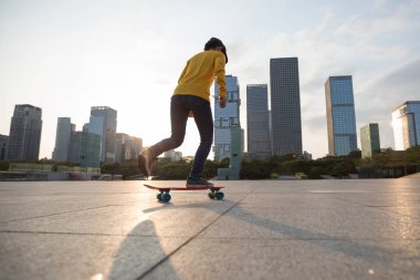 Shenzhen, Çin 'in şehir merkezinde günbatımında şık bir kadın kaykay yapıyor.