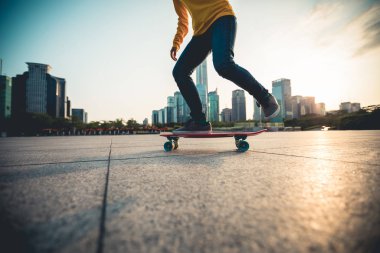 Gündoğumunda şehir meydanında kaykay yapan sıradan bir bayan kaykaycı.