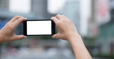 Bulanık şehrin modern akıllı telefonuyla fotoğraf çeken kadının elleri