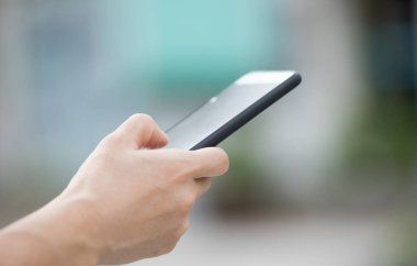 Modern akıllı telefonu açık havada kullanan bir kadın eli.