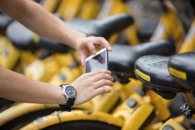 Şehirde akıllı telefon kullanan ve QR paylaşımlı motor kodunu tarayan bir kadının elleri